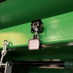 A square LED work light and a hanging chain under the body of an ACJ GreenLoader.