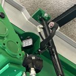 A small work light and hydraulic hoses at a joint in the GreenLoader frame.