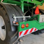 Rear corner of a GreenLoader indoors, showing the lights, striped bumper and a red warning triangle.