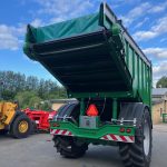 Side view of a GreenLoader with the body raised, parked in a yard.