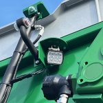 A square work light mounted next to a hydraulic motor on a GreenLoader.