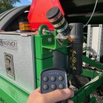 A remote control held beside the GreenLoader beacon and control box.