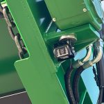 A work light and curved hydraulic hoses at a corner of the GreenLoader frame.