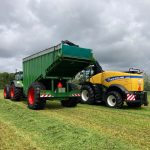 Rear view of a yellow forage harvester filling a GreenLoader on grass.