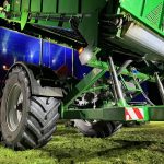 Low night view of a GreenLoader wheel, lift cylinders and raised body.