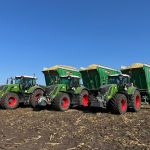 Four tractors with GreenLoaders lined up facing the camera on a muddy field.