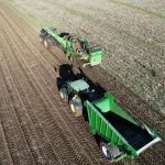 Overhead view of several GreenLoaders, one unloading a root crop from its conveyor.