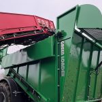 A GreenLoader side conveyor dropping a root crop, with GREEN LOADER lettering on the body.