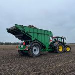 Rear three-quarter view of a GreenLoader carrying a root crop.