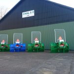 Four green ACJ PowerWinch units lined up on paving in front of a dark workshop.