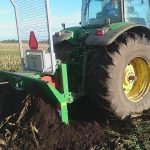 Rear wheels of a green tractor with a PowerWinch cable running into a ploughed field.