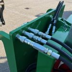 Hydraulic hoses and metal couplings on the side of a green PowerWinch.
