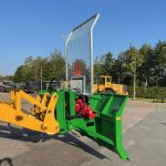 A PowerWinch on a yellow loader arm, with the mesh guard raised.
