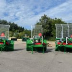 Three PowerWinch units parked in a row on a yard in front of trees.