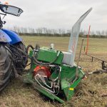 A PowerWinch with a red motor beside the front wheel of a blue tractor.