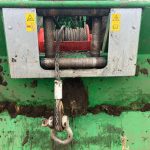 Close-up of a muddy winch drum with the wire rope and hook.