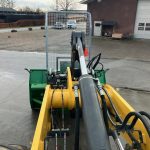 A PowerWinch carried on the arm of a yellow loader in a yard.