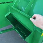 Open storage compartment inside a PowerWinch, with a hand at the lid.