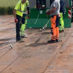 Two operators in high-visibility clothing holding ropes beside a numbered Twin Power unit.