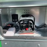 Open side compartment of a Twin Power with a battery, hoses and control parts.